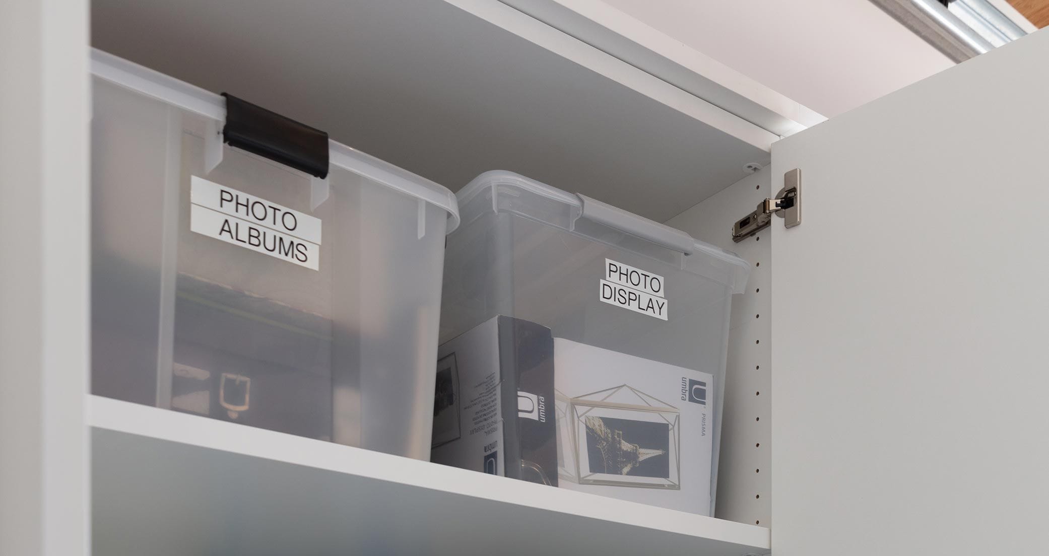 Custom cabinets with shelving to hold family photos in storage bins in garage by California Closets
