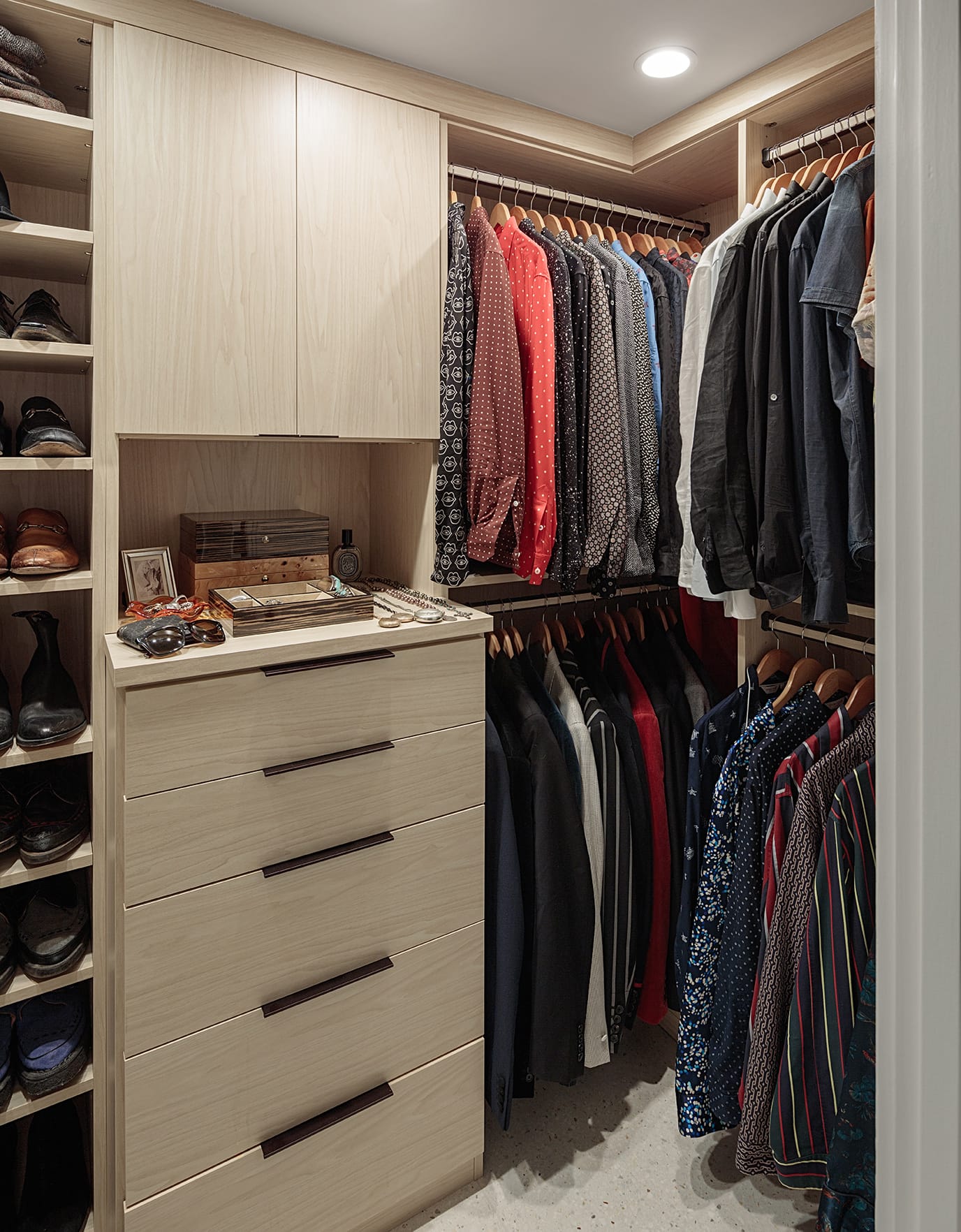 Walk in closet with custom dresser and built in shoe storage in a light wood finish with metal hardware