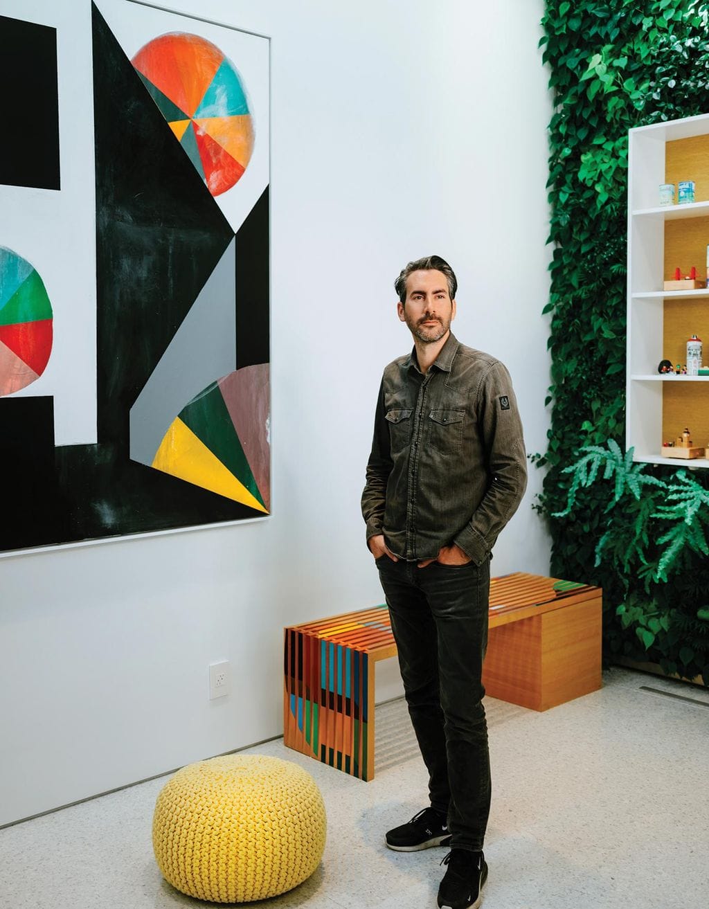 Dan Brunn, LA architect in the home he built with eco-friendly materials, stands in his room with a vine covered wall, as seen in Ideas of Order Magazine.
